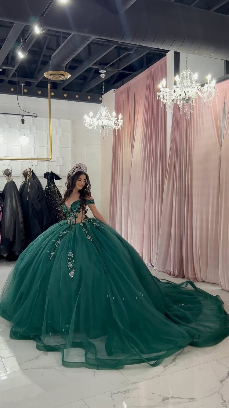 Young woman in a voluminous dark green ball gown and tiara in a boutique.