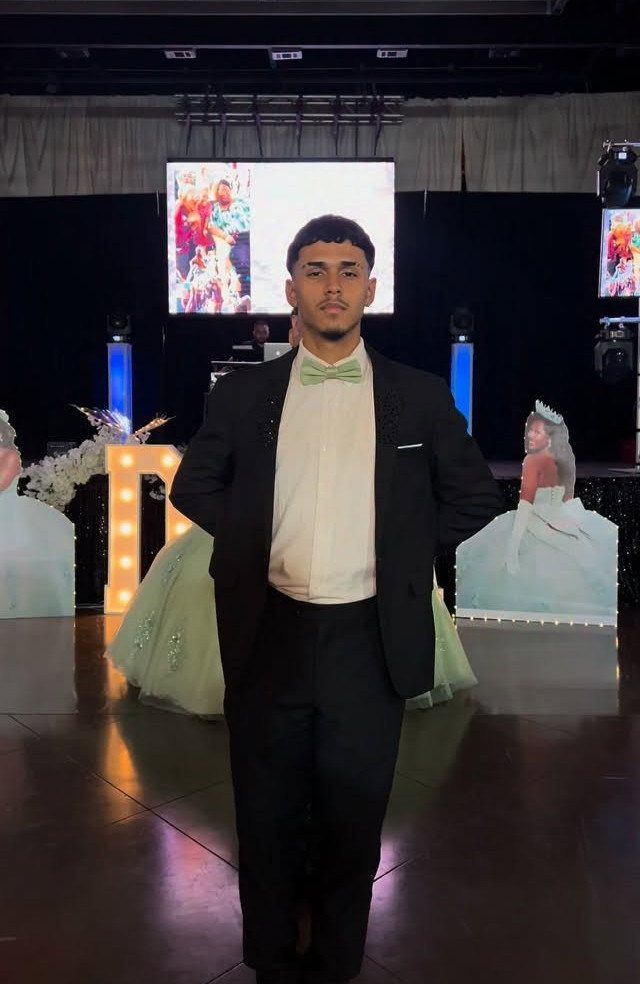 Young man in a black suit and light green bow tie at a party.