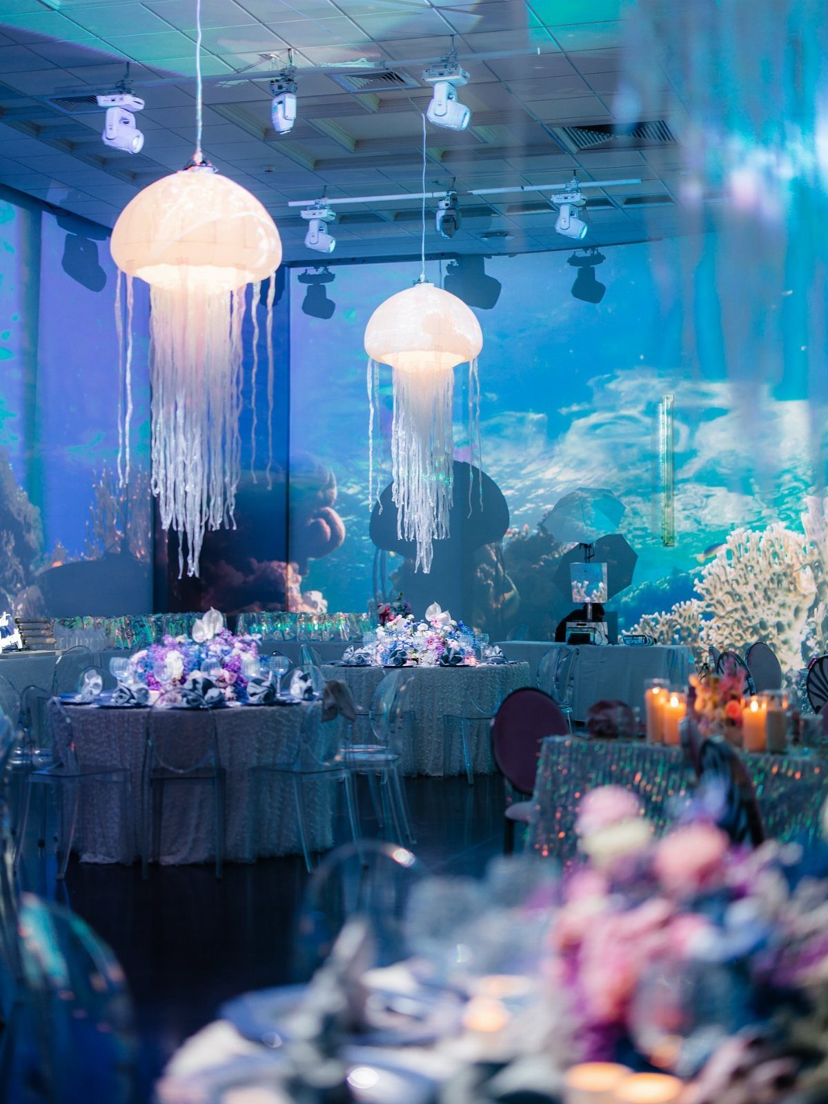 Glowing jellyfish lamps and coral reef backdrop in an under the sea event space