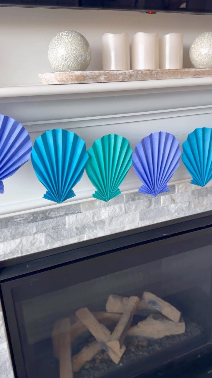 Blue and purple pleated paper seashells decorating a white fireplace mantel