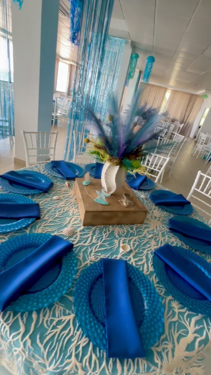 Under the sea themed table setting with blue plates and coral tablecloth.