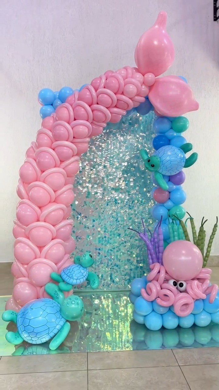 Balloon mermaid tail arch with sea turtles and octopus against a sequin backdrop.
