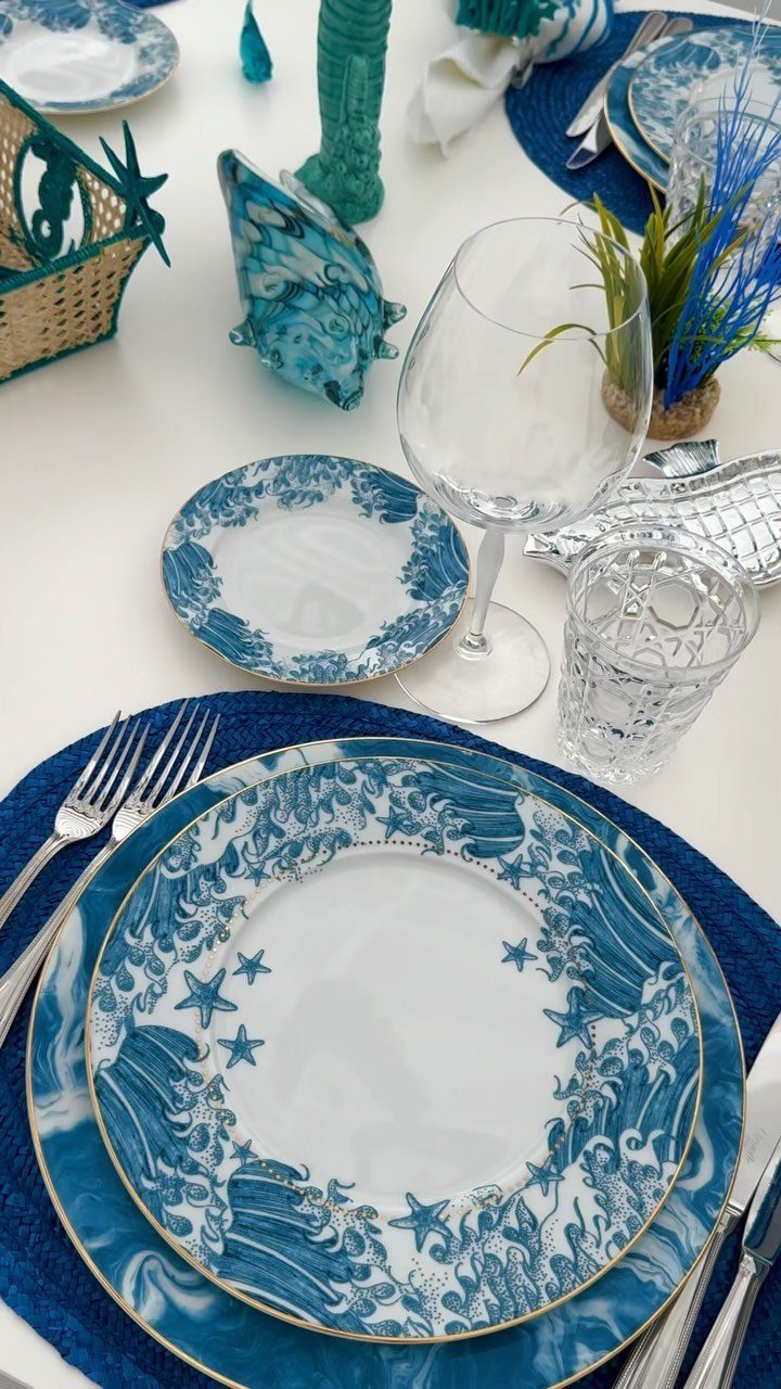 Ocean-themed table setting with blue and white wave patterned plates and silver flatware.