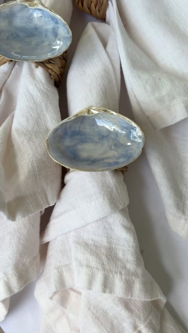 White linen napkins with blue and white marbled shell-shaped ceramic napkin rings.