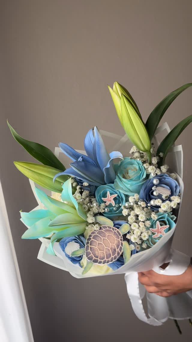 Blue and teal floral bouquet with starfish and a turtle decoration.