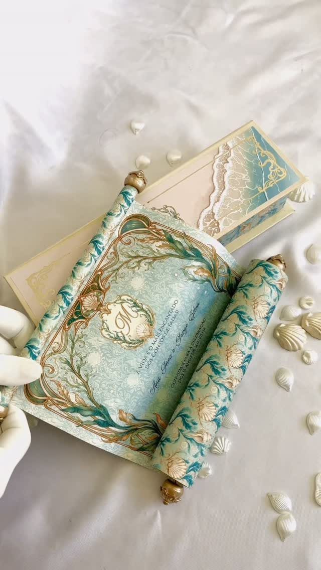 Under the sea themed wedding invitation scroll with seashells on white fabric.