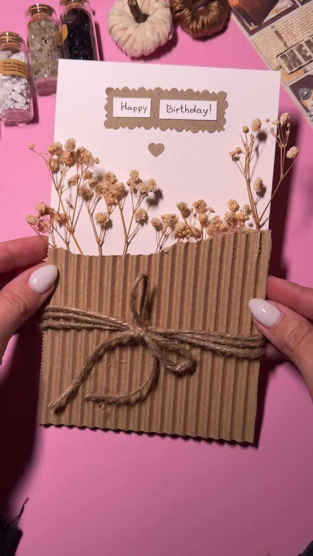 Handmade birthday card with corrugated cardboard, twine bow, and small dried white flowers.