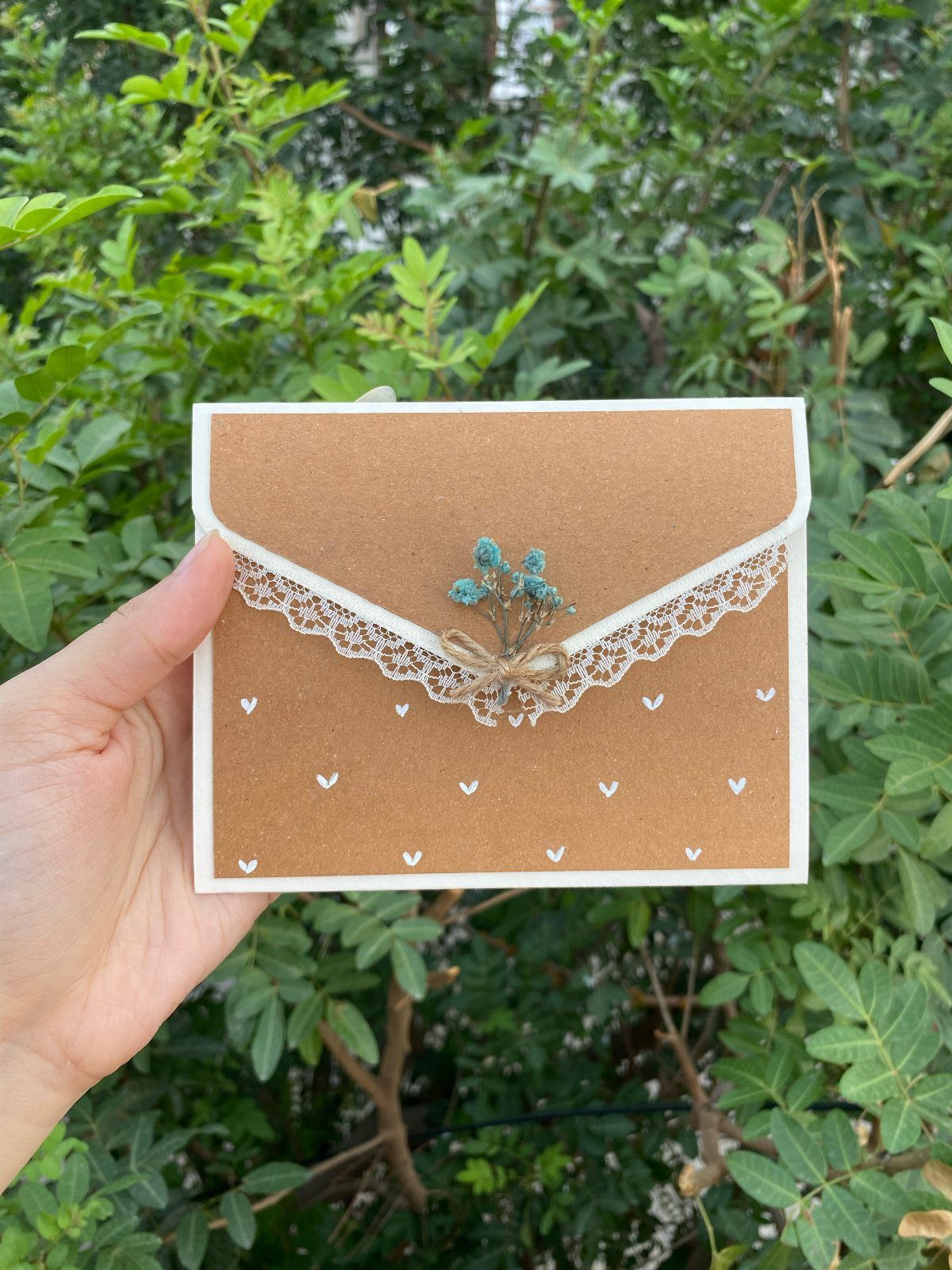 Kraft paper birthday card with lace trim, twine bow, and small blue flowers.