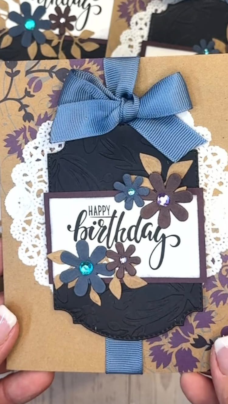Handmade birthday card with layered paper flowers, blue ribbon, and white lace trim.