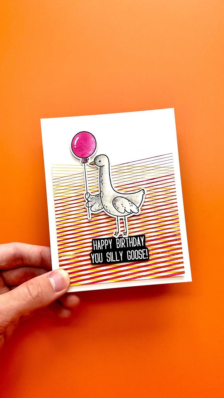 Birthday card featuring a stamped goose with a pink balloon on striped paper.