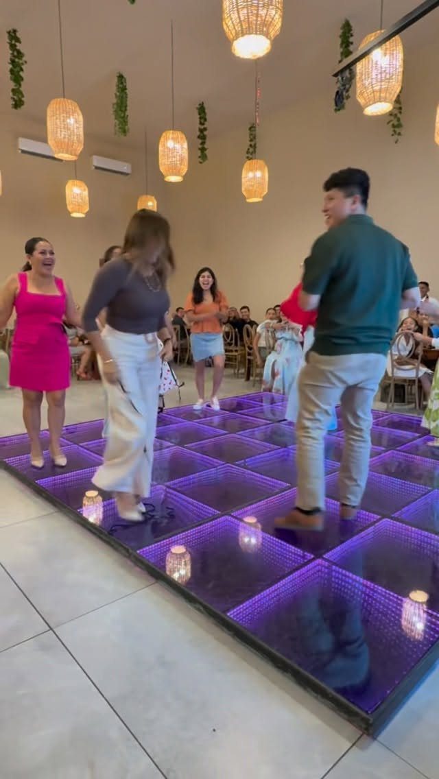 People dancing on a purple LED illuminated dance floor in a decorated room.