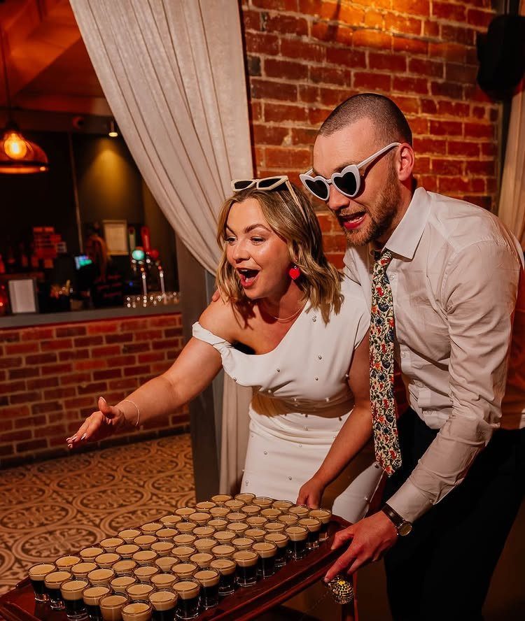 Couple reacting with excitement to a wooden trolley filled with many shot glasses.