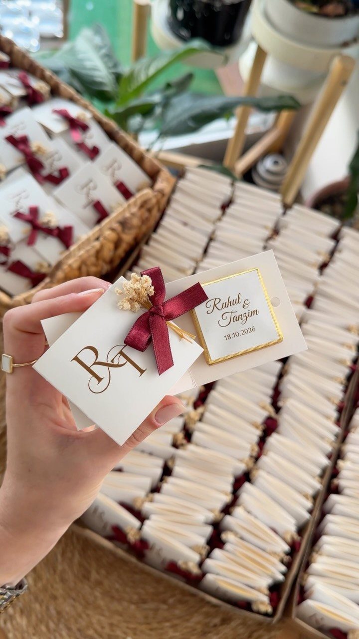Personalized white chocolate bars with burgundy ribbons and dried flowers for wedding favors.
