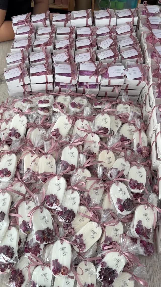 White gift boxes and floral soaps wrapped in plastic with purple ribbons.