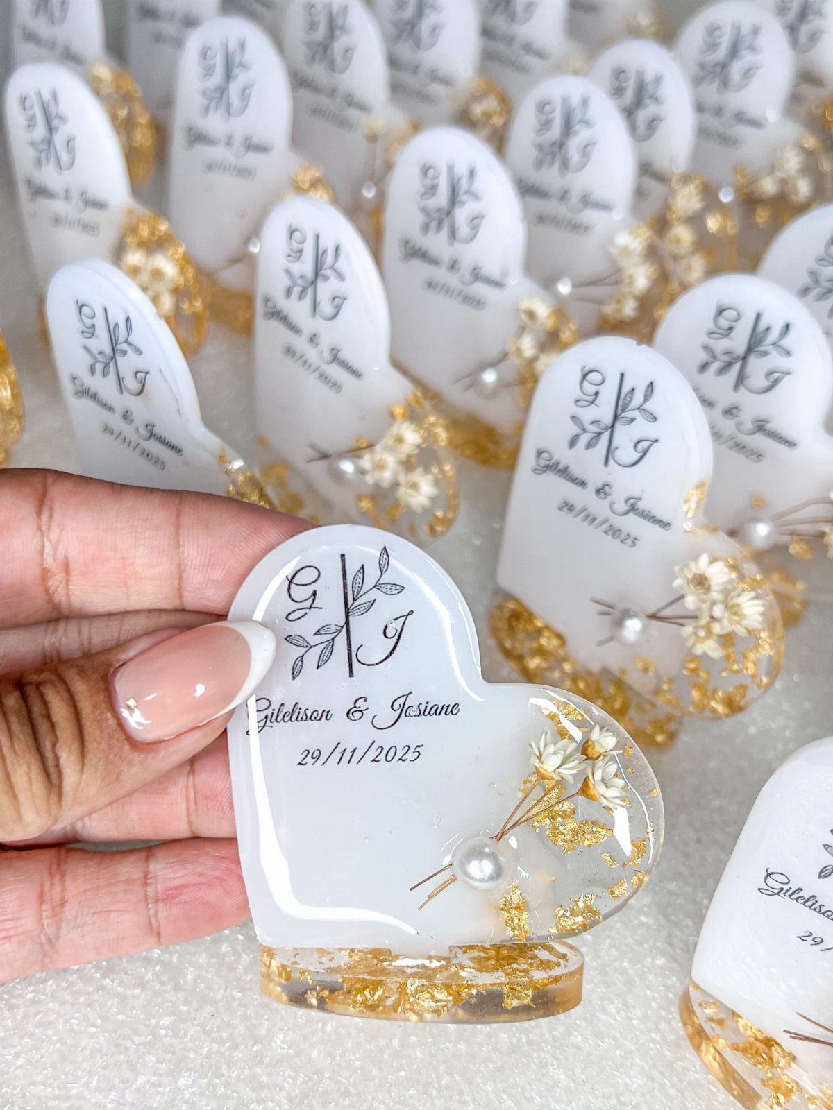 Heart-shaped white resin keychains with gold flakes and dried flowers for wedding favors.