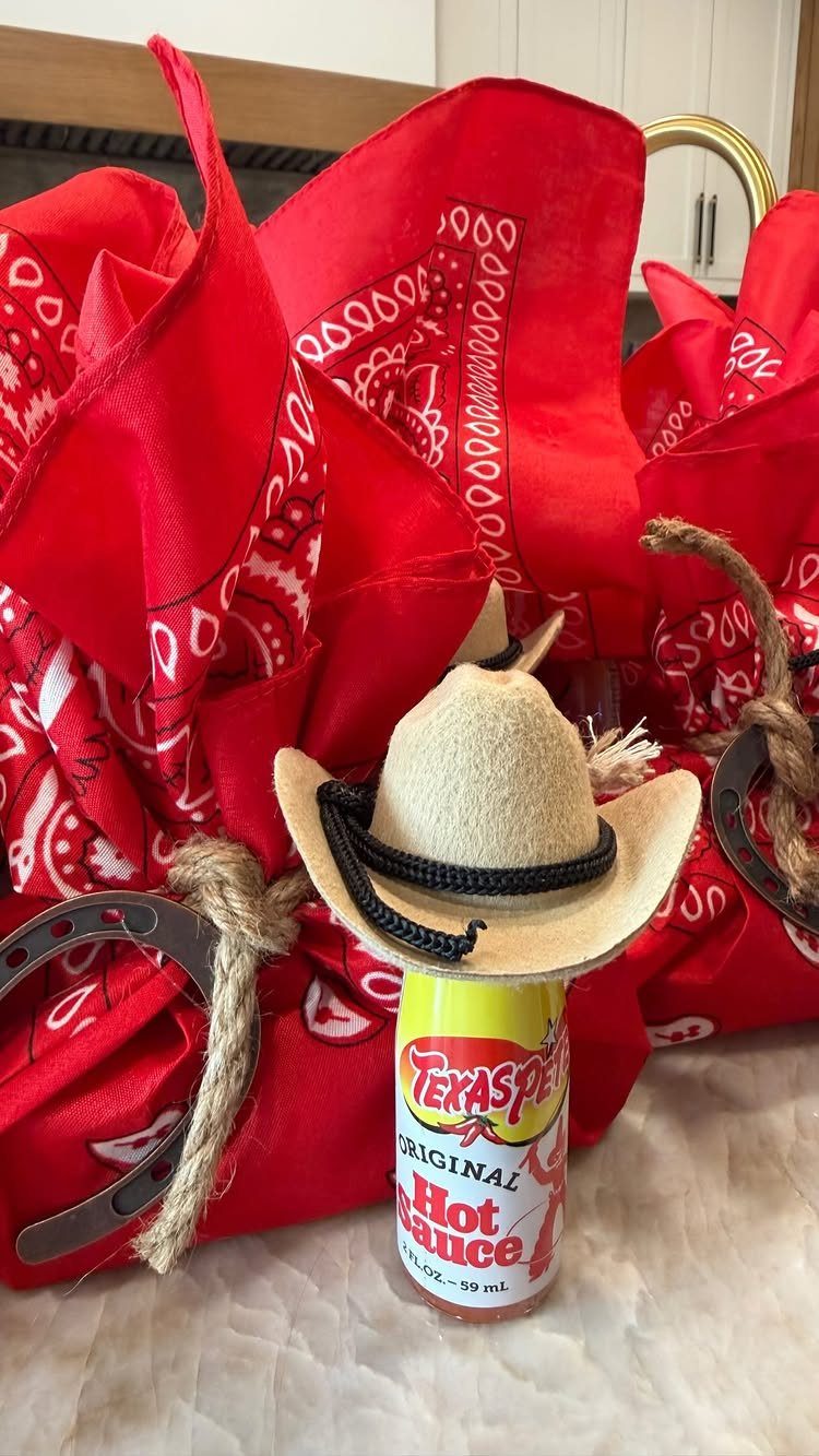Small hot sauce bottle wearing a tiny cowboy hat with red bandanas and horseshoes.