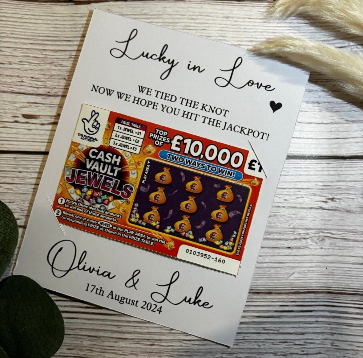 Lottery scratch card attached to a personalized wedding favor card on wooden background.