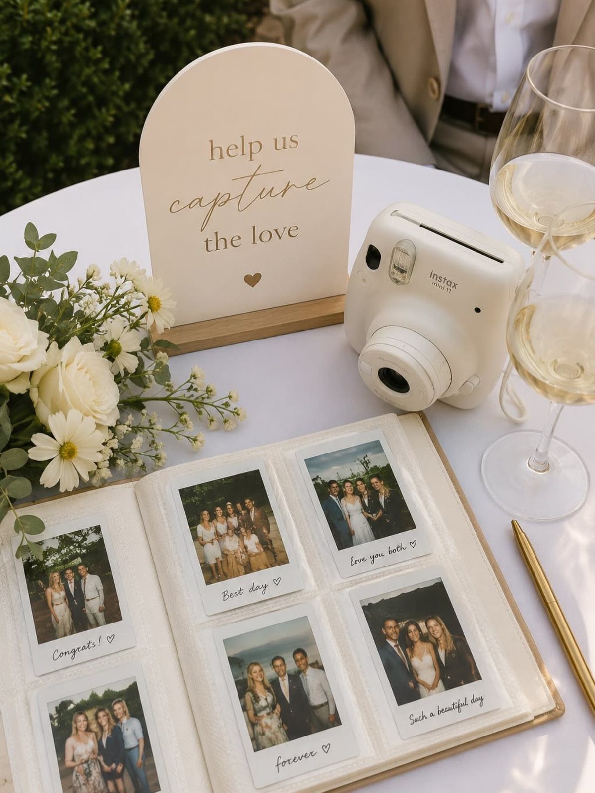 Instant camera and guestbook with Polaroid photos on a wedding reception table.