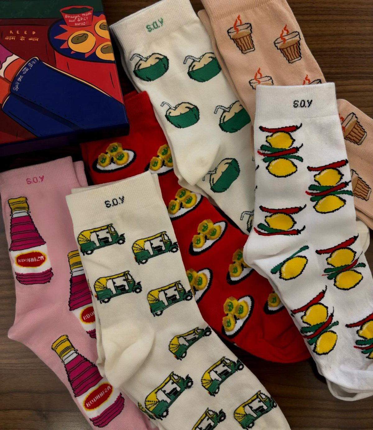 Patterned socks with food and vehicle prints laid on a wooden surface.