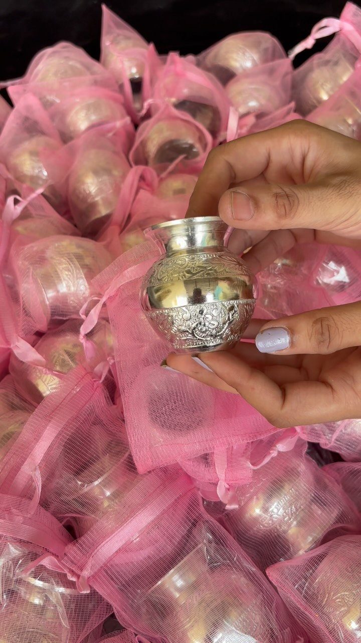 Ornate silver metal pots in pink mesh drawstring bags as wedding favors.