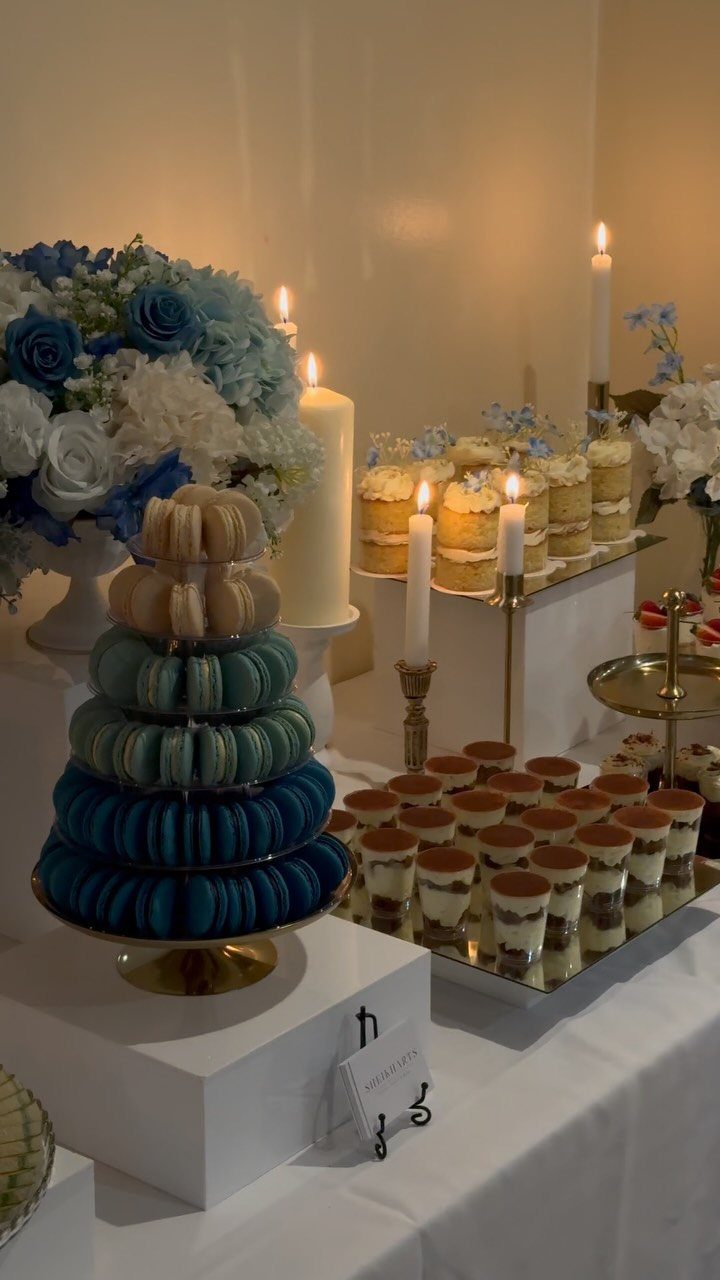 Tiered macaron tower and dessert cups on a white wedding reception table.