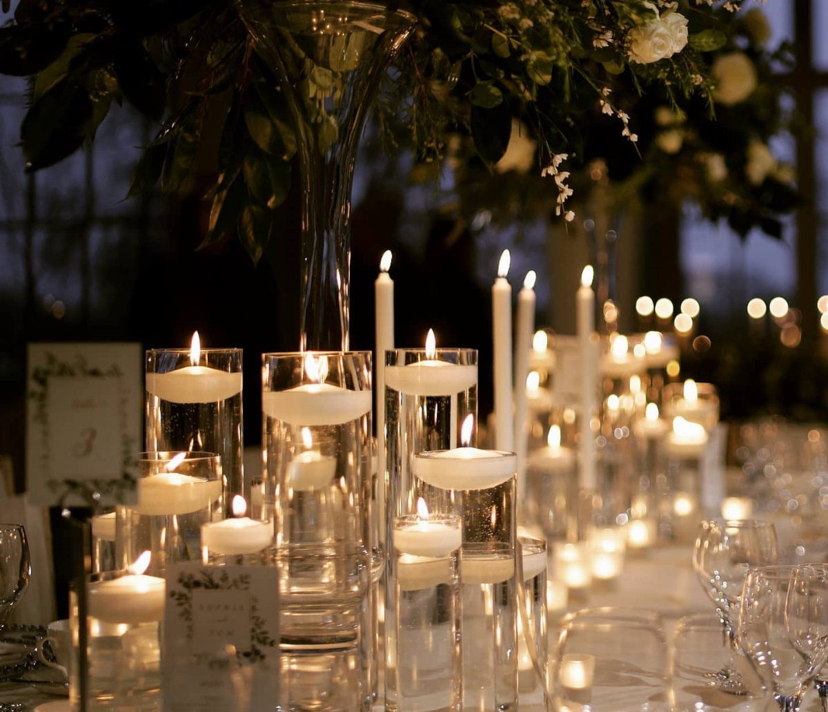 White floating candles in glass cylinders and taper candles on a wedding table