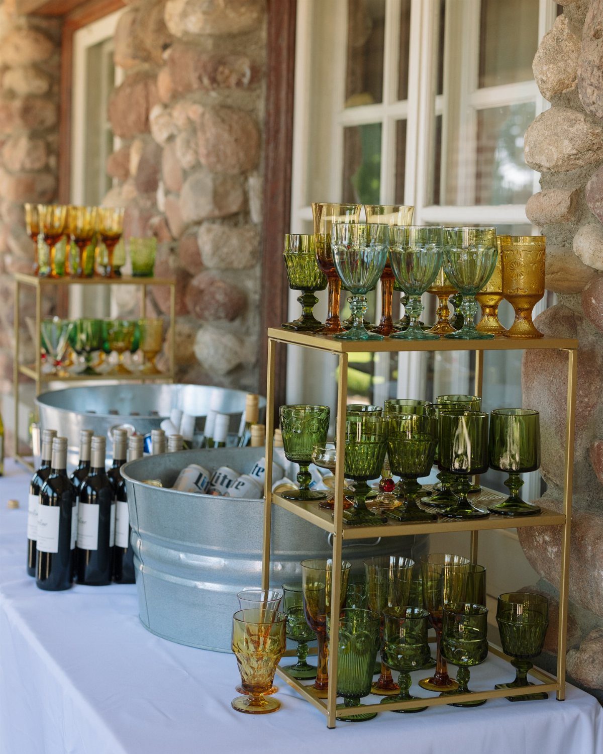 Colored green and amber glassware arranged on gold tiered shelves at a wedding reception.